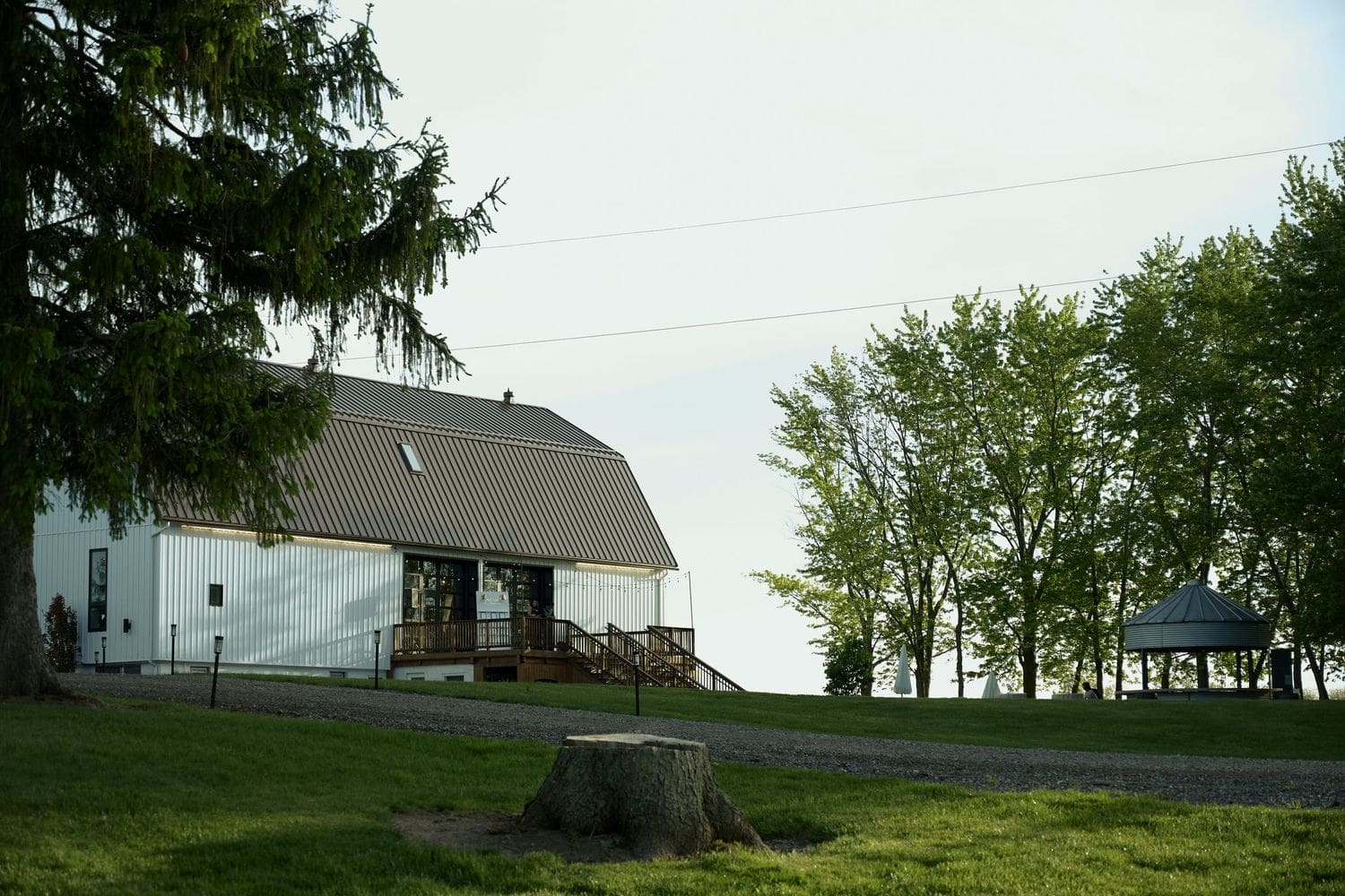White barn with gambrel roof on a green hill at Crescent Hill Acres wedding venue in Canada