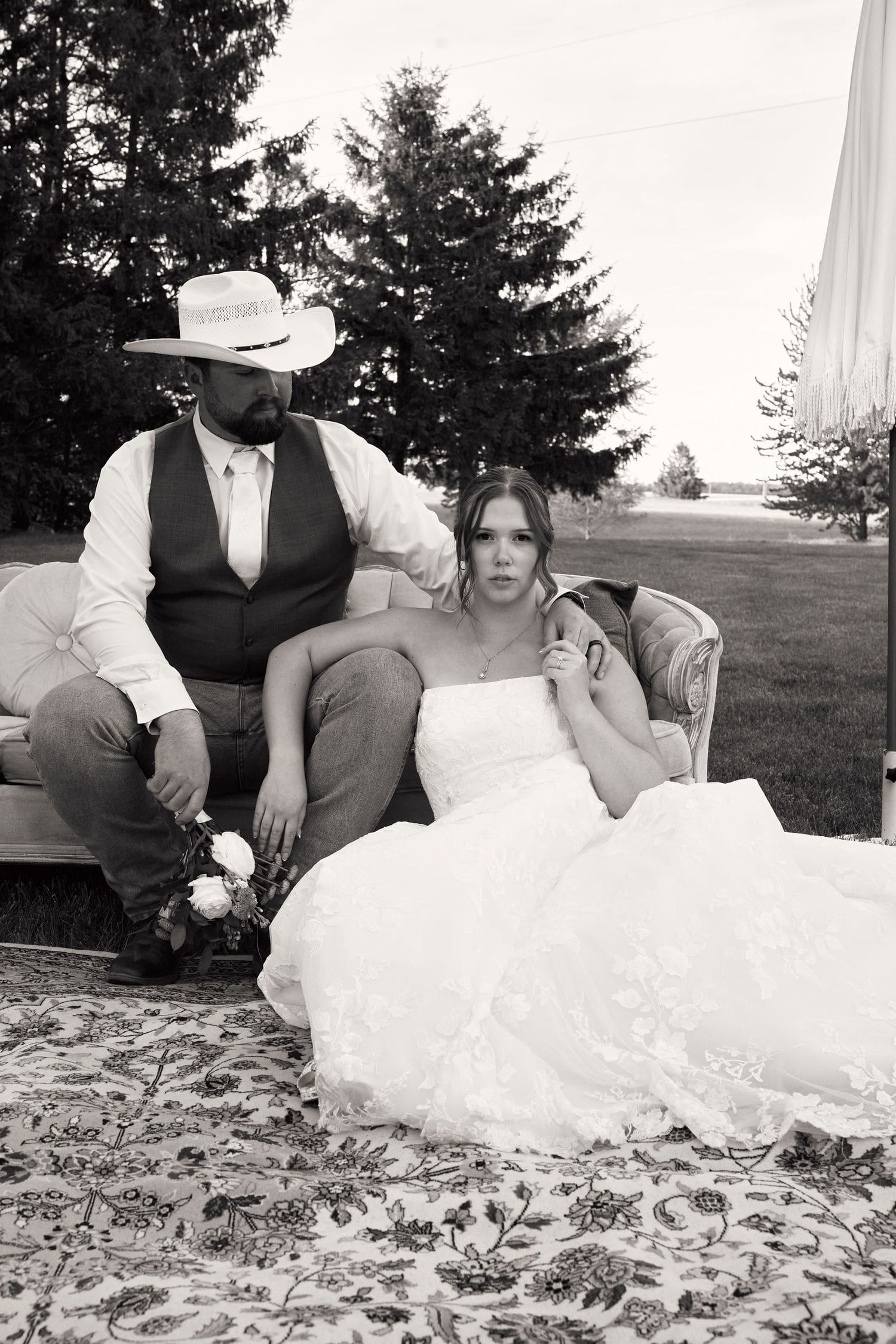 Black and white portrait of bride and groom seated on a vintage sofa at their Crescent Hill Acres wedding