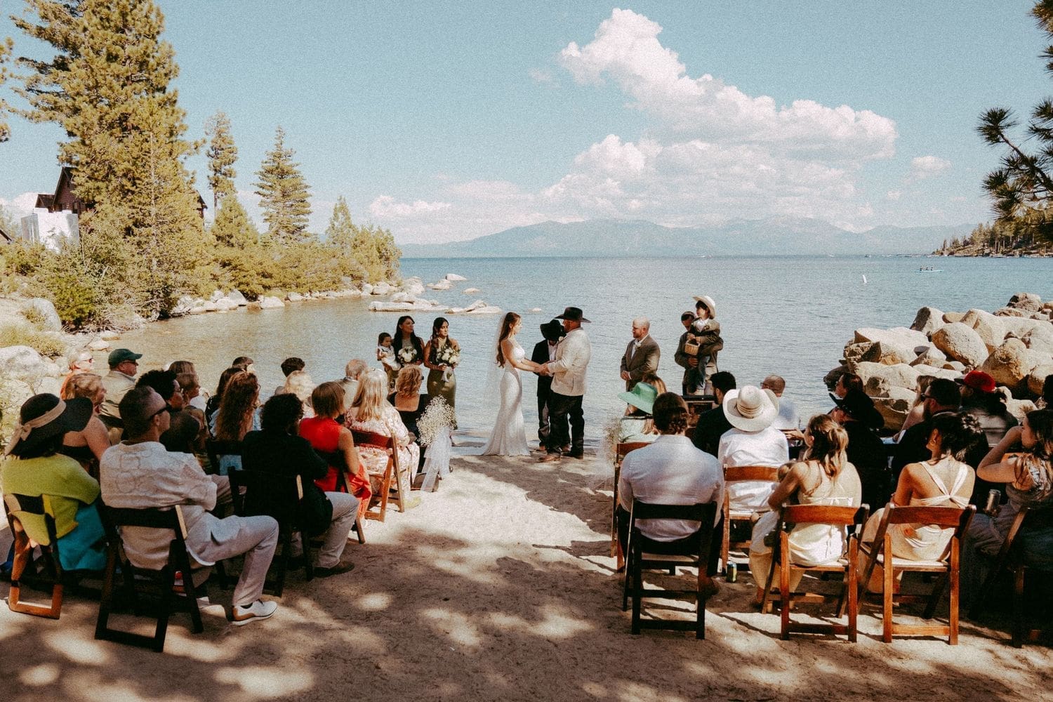 Outdoor lakeside wedding ceremony with guests seated on wooden chairs and the couple at the altar at Lake Tahoe