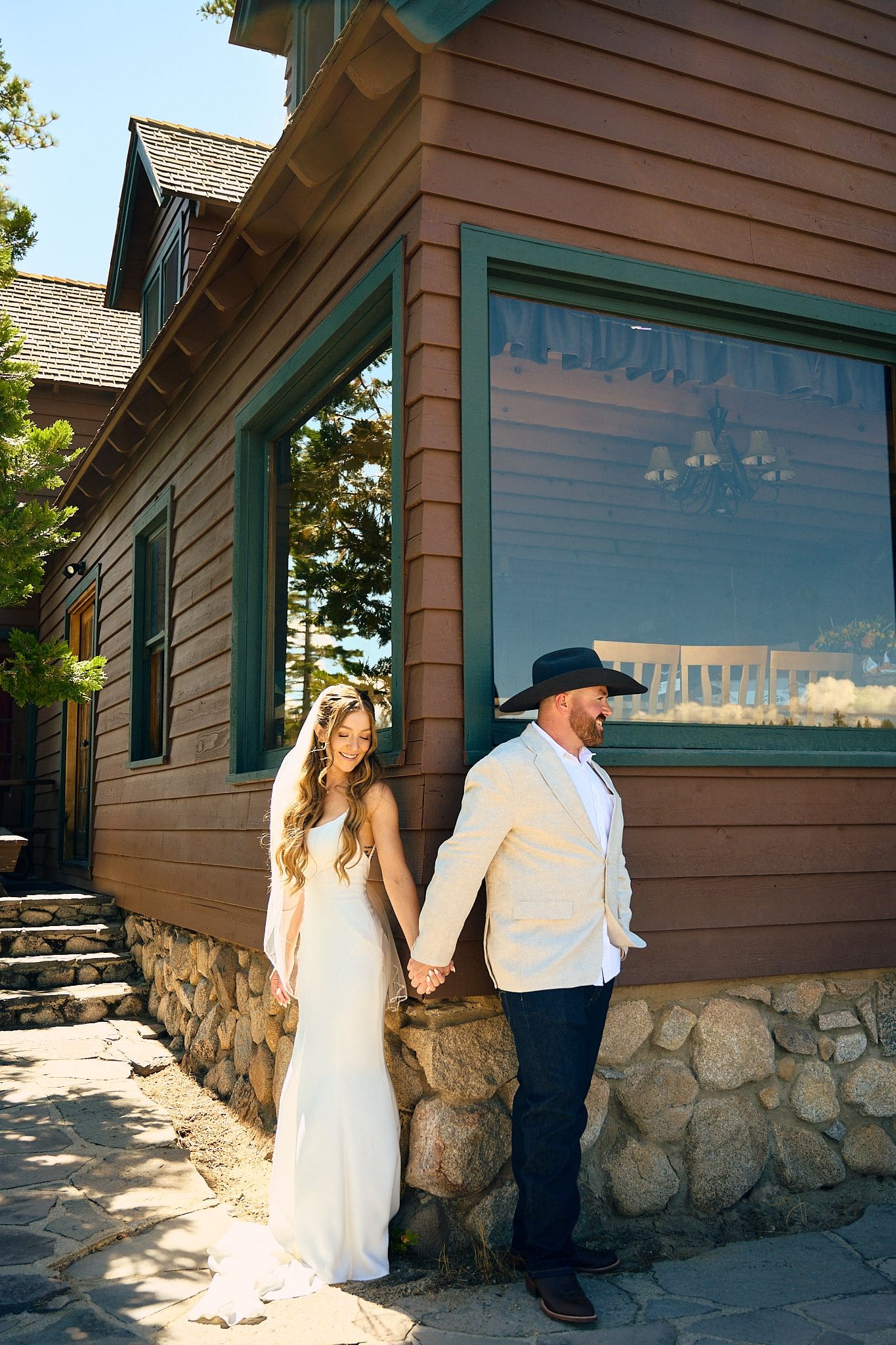 Bride and groom holding hands outside a rustic stone and wood building on their Lake Tahoe wedding day