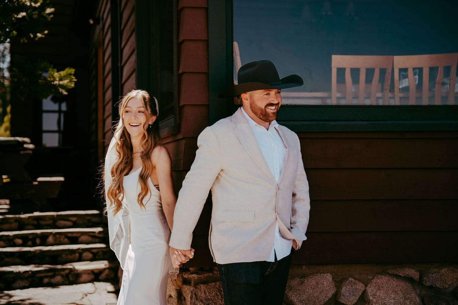 Bride and groom holding hands outside a rustic wooden building at their small Lake Tahoe wedding