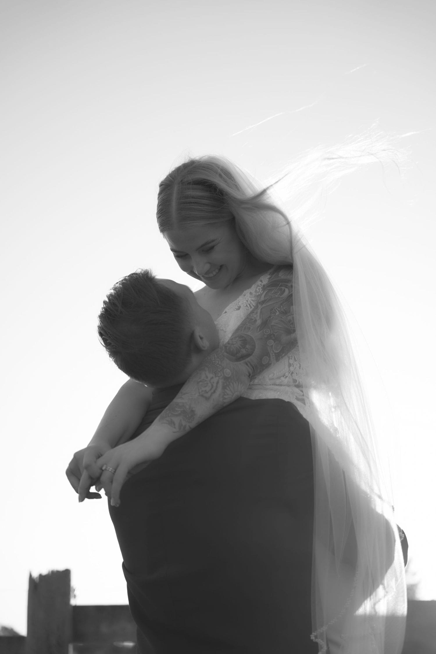 Black and white photo of groom lifting bride in wedding dress and veil at Sovignon Ranch in Sebastopol, California