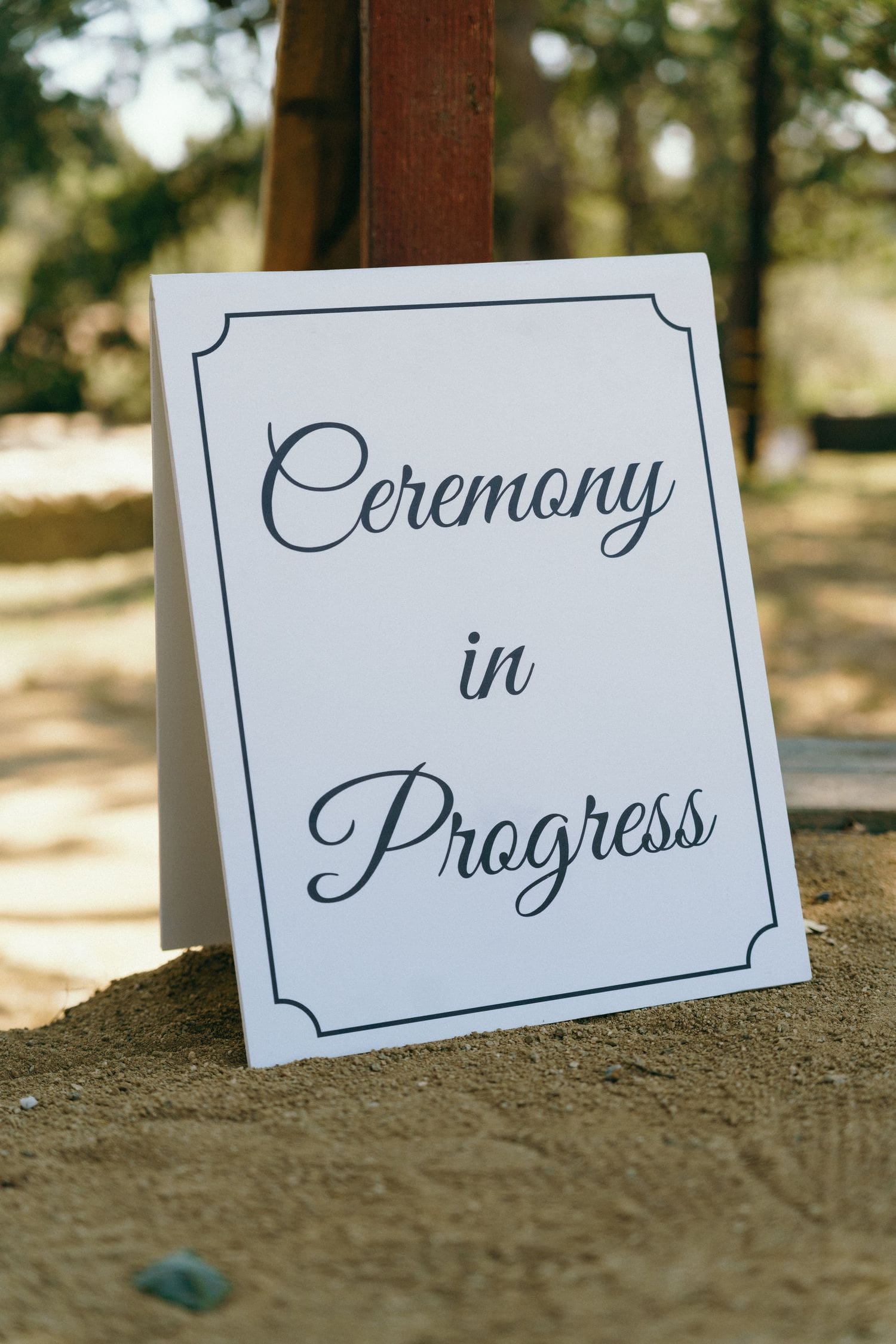 Ceremony in progress sign displayed outdoors among trees at a Sebastopol wine country wedding