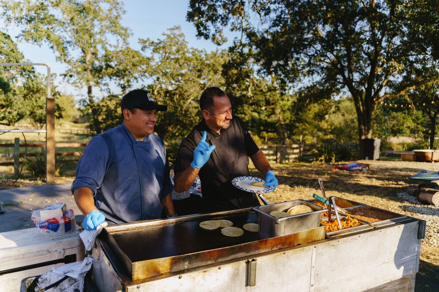 Groomsmen cooking tortillas on an outdoor griddle during wedding day prep at Sovignon Ranch