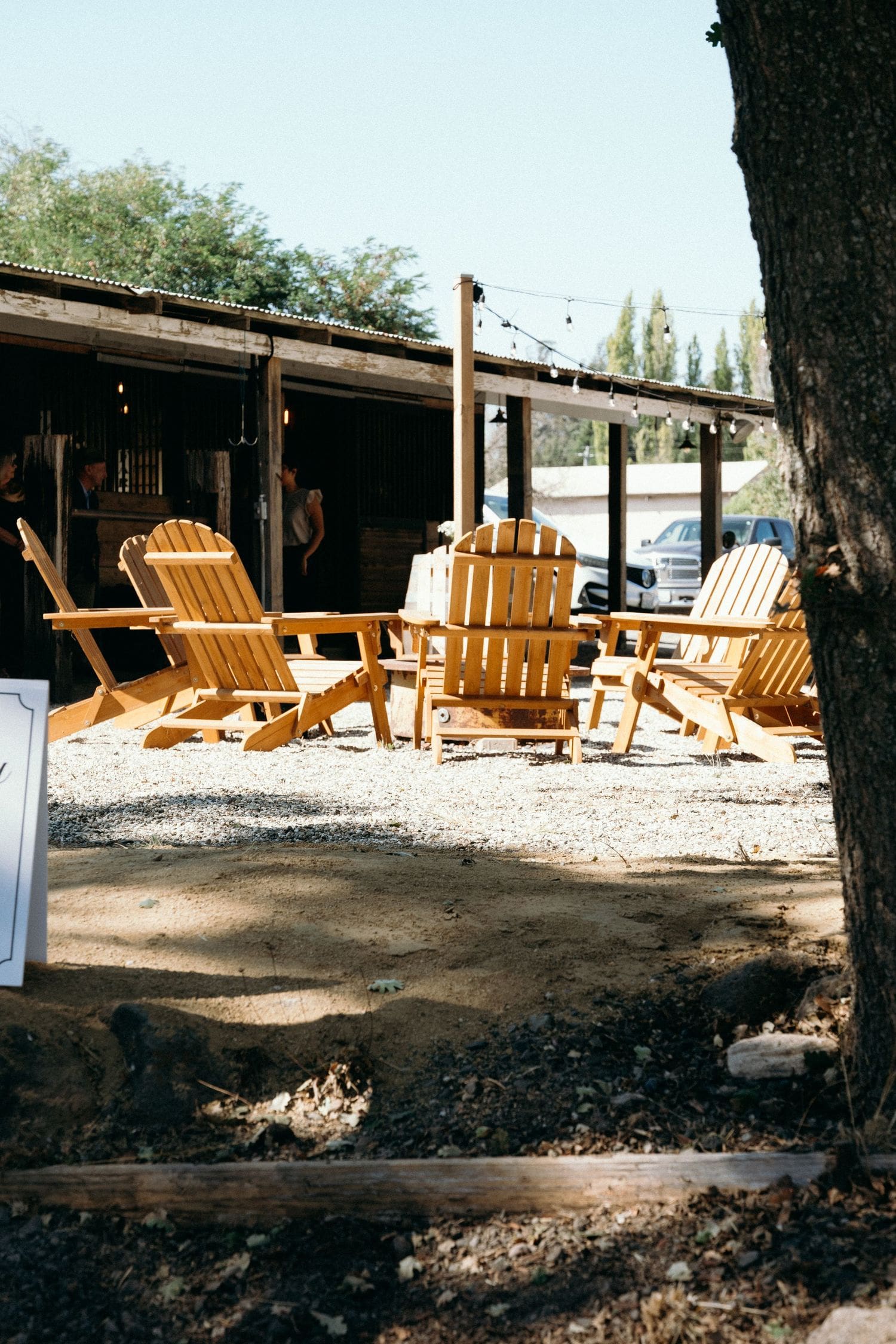 Adirondack chairs arranged in a circle on a gravel patio with string lights at a Sonoma County wedding reception
