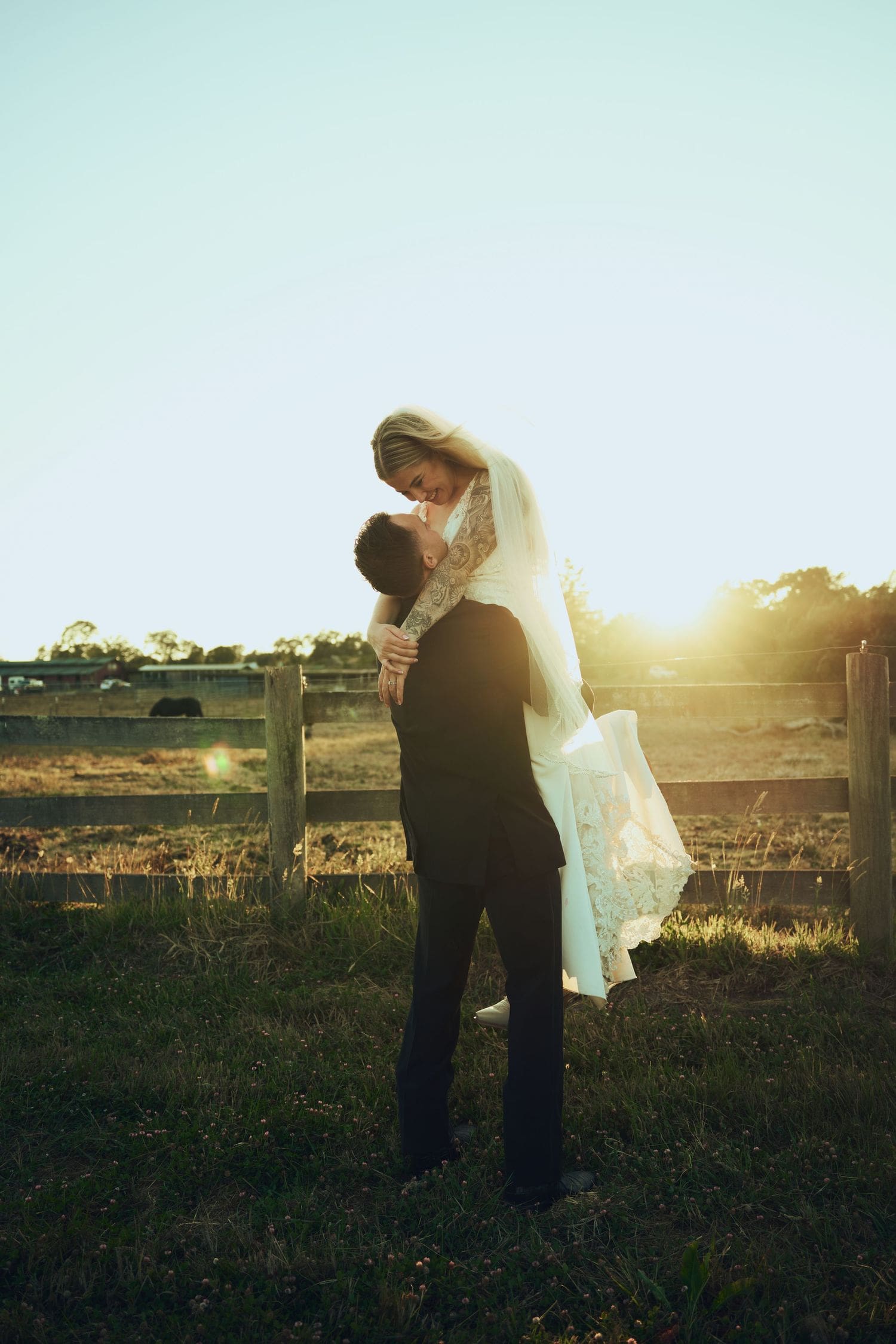 Bride and groom embracing at sunset near a rustic fence at Sovignon Ranch in Sonoma County