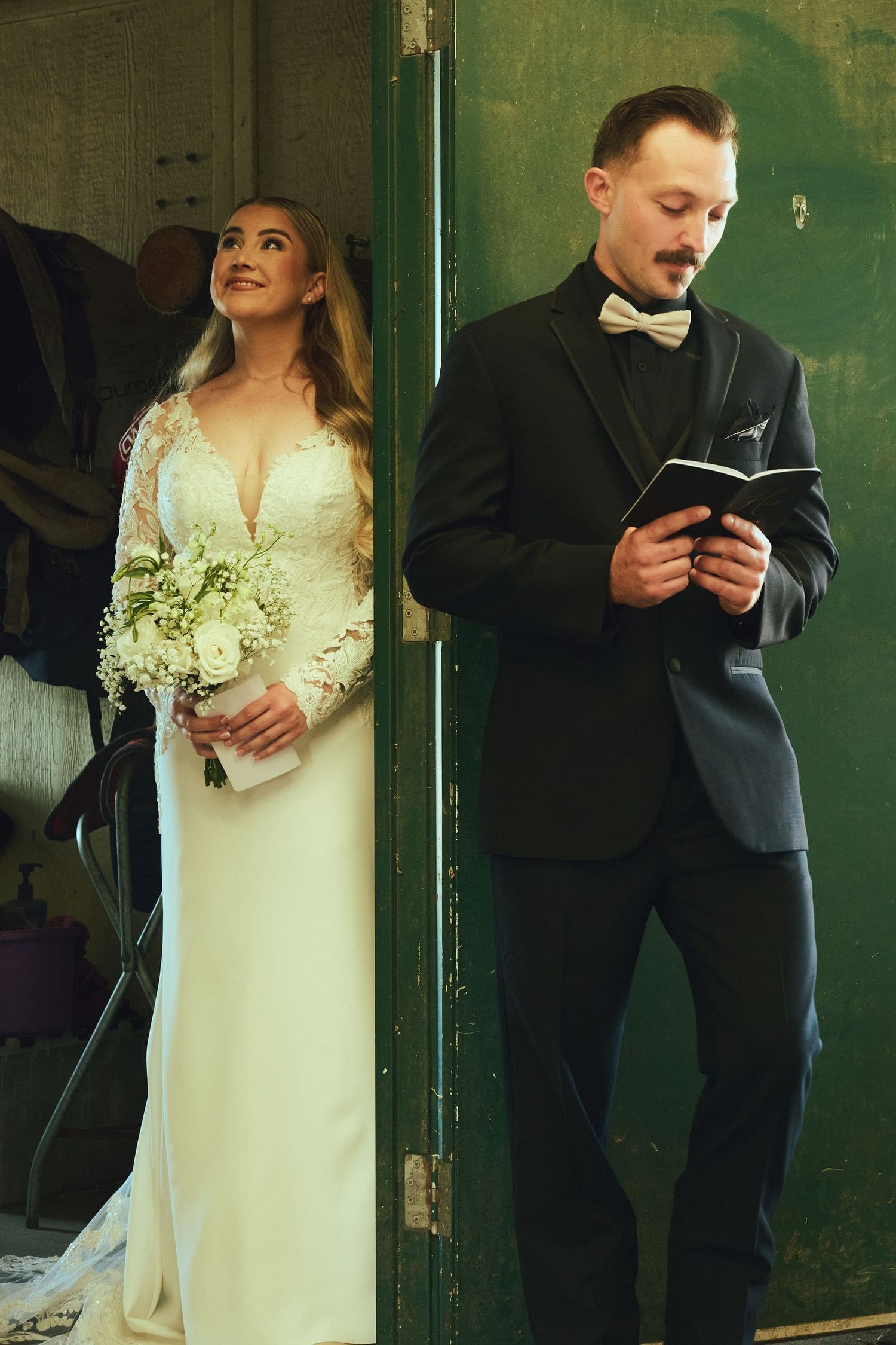 Bride in lace gown holding bouquet beside groom reading vows during their Sebastopol ceremony