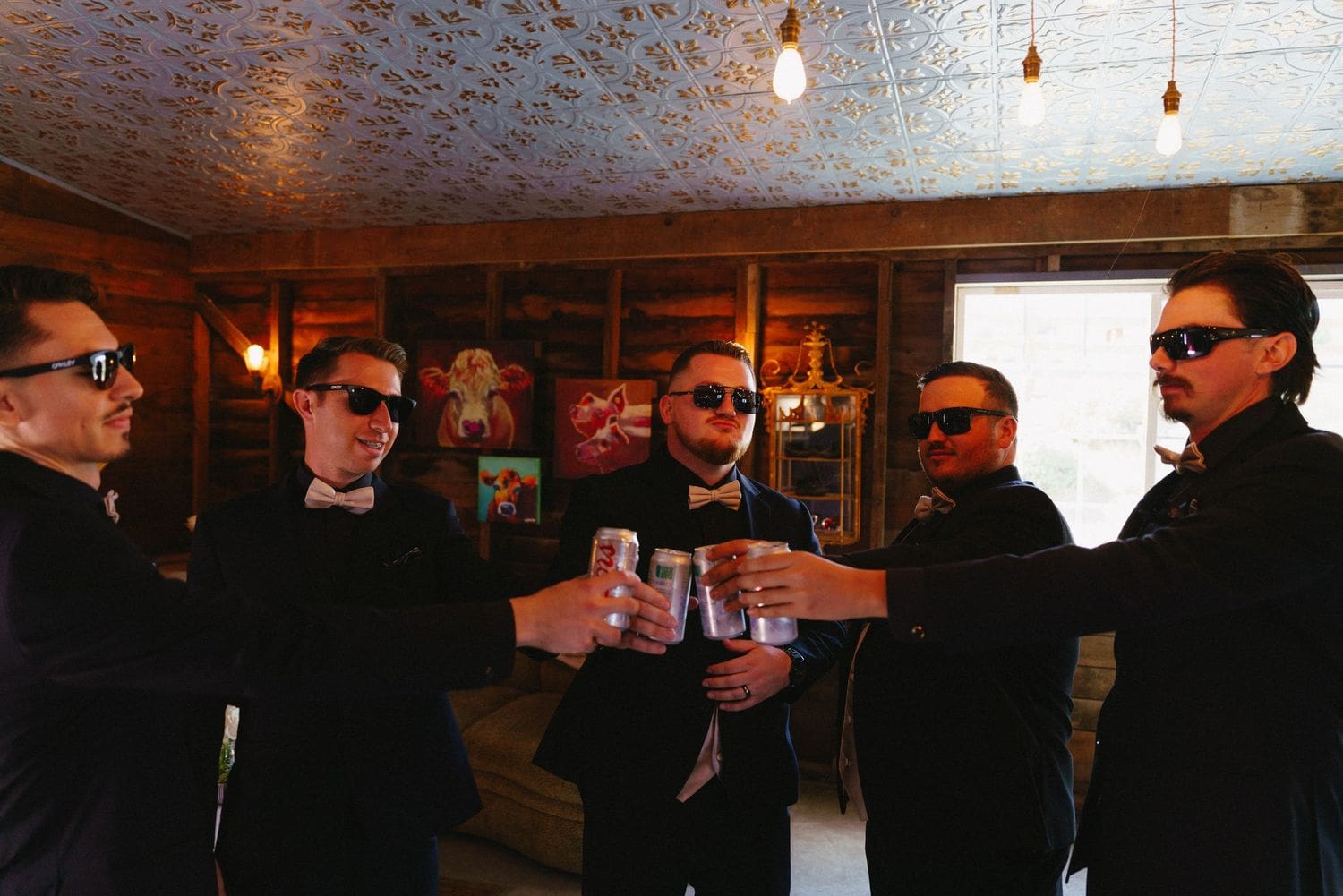 Five groomsmen in black tuxedos toasting with drinks at a Sonoma County wedding reception